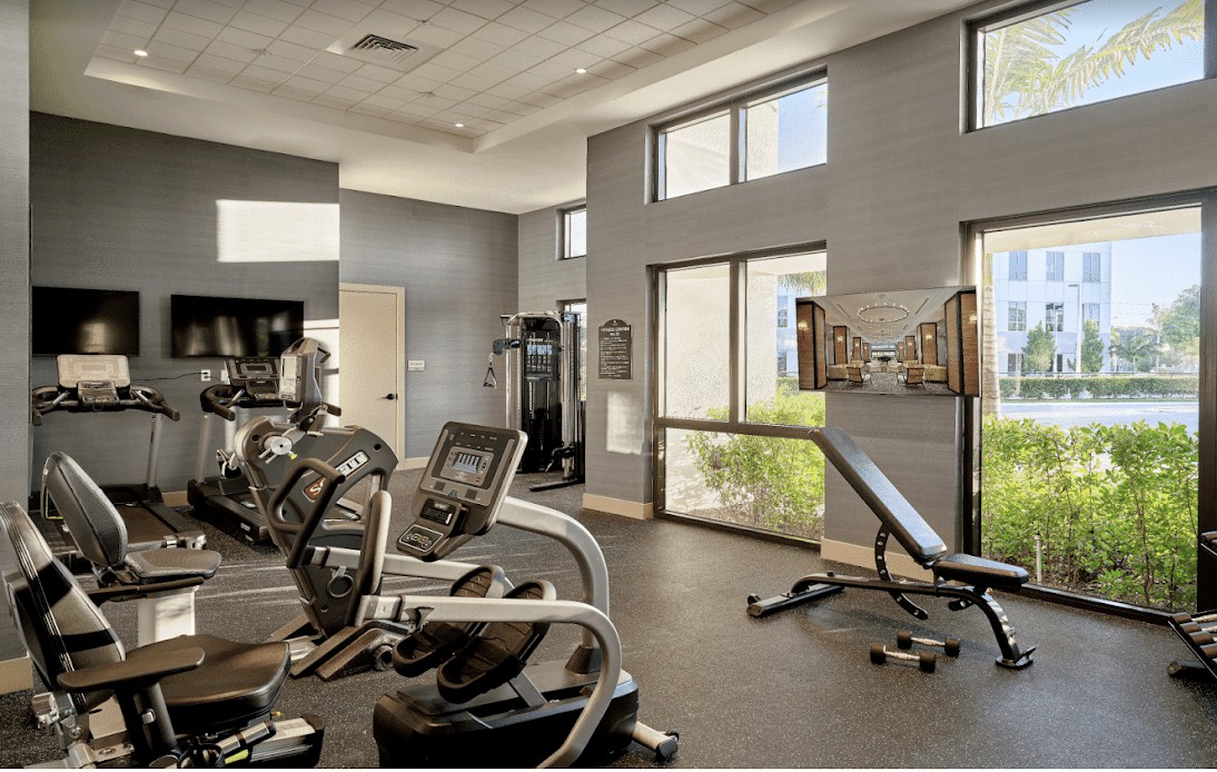 A modern gym interior featuring various exercise equipment including treadmills and a bench press.