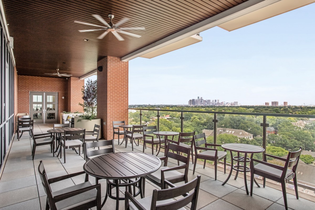 An outdoor patio with tables and chairs overlooking a cityscape.