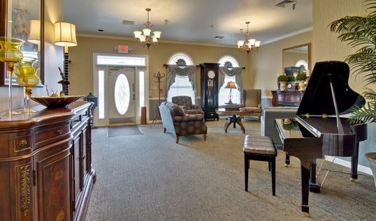 A well-furnished living room featuring comfortable seating, large windows, and elegant chandeliers.