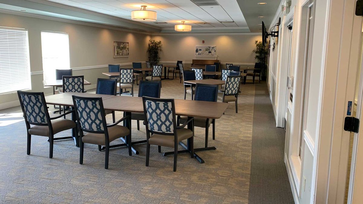 An empty conference room with tables and chairs arranged for a meeting, featuring soft lighting and a piano in the background.