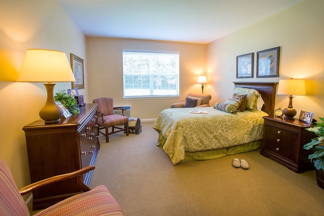 A cozy bedroom with a neatly made bed, lamps, and elegant furnishings.