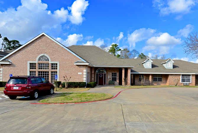 A large residential building with a driveway under a partly cloudy sky.