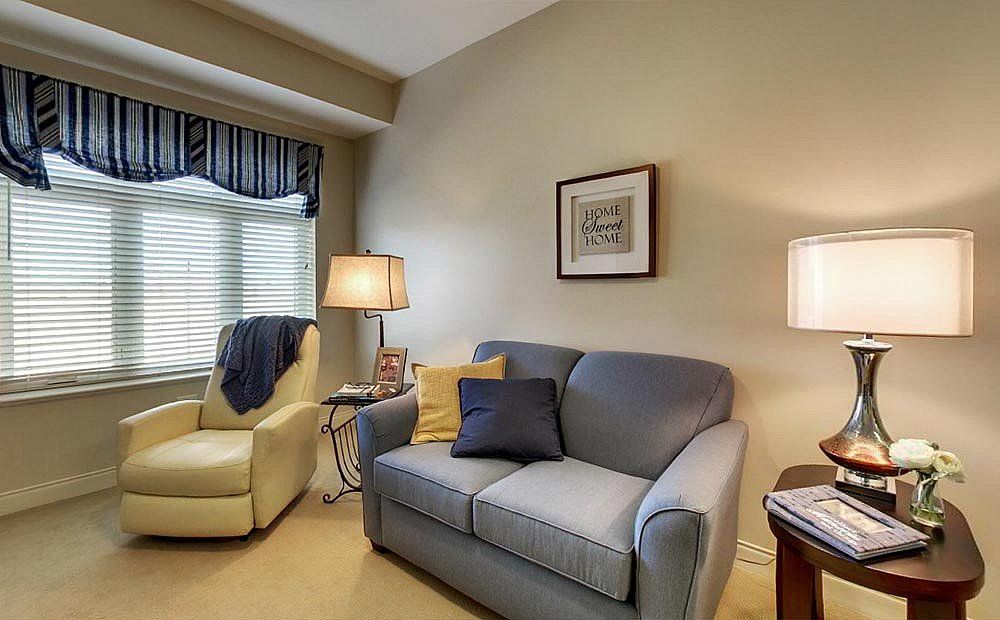 A cozy living room with a sofa, armchair, and warm lighting.