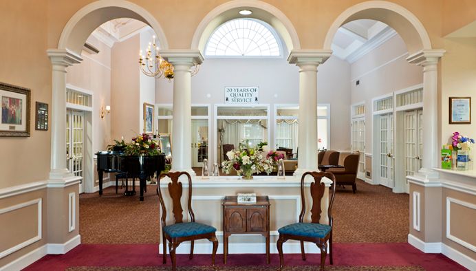 A traditional lobby interior featuring columns, floral arrangements, and classic chairs.