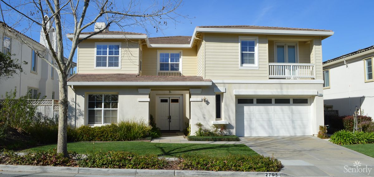 A two-story suburban house with a garage and well-maintained lawn.