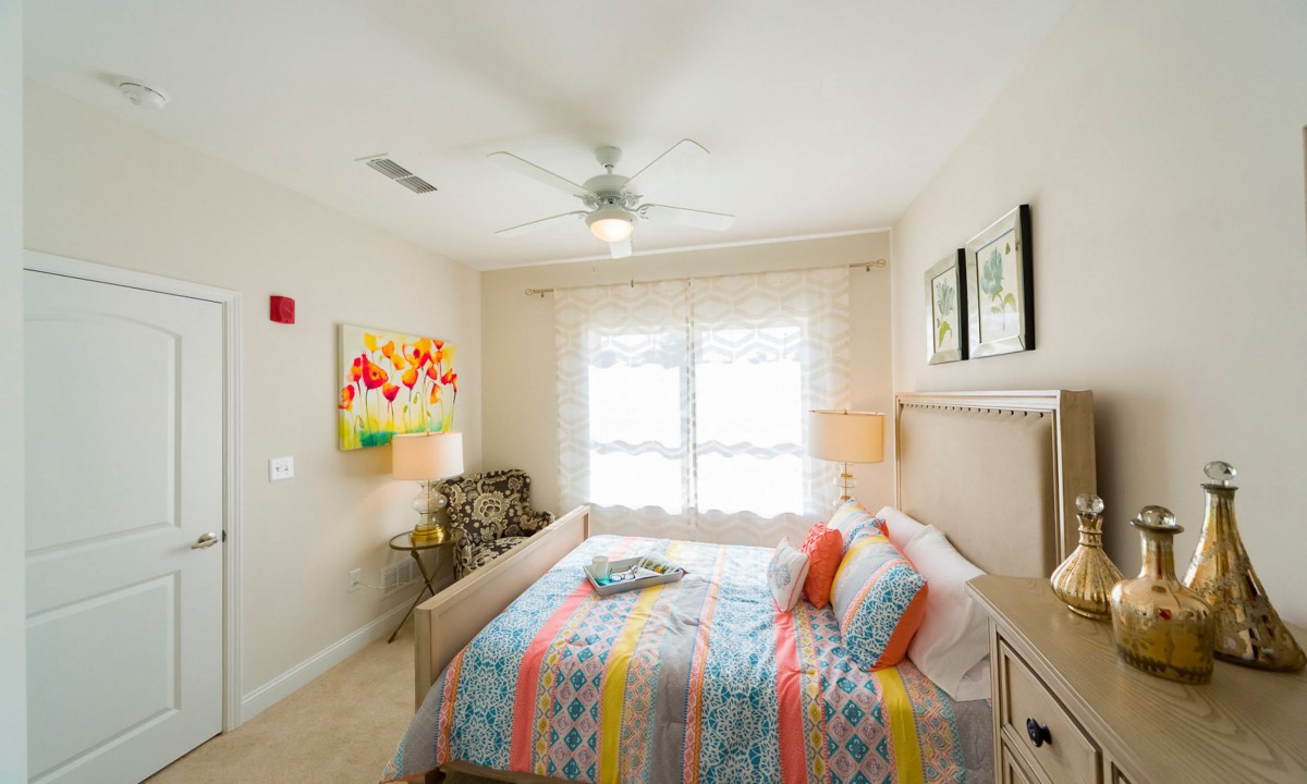 A bright and colorful bedroom with modern decor, featuring a ceiling fan and plenty of natural light.