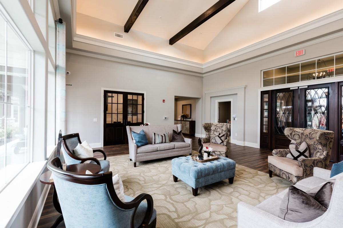 A spacious living room with elegant furniture and high ceilings featuring wooden beams.
