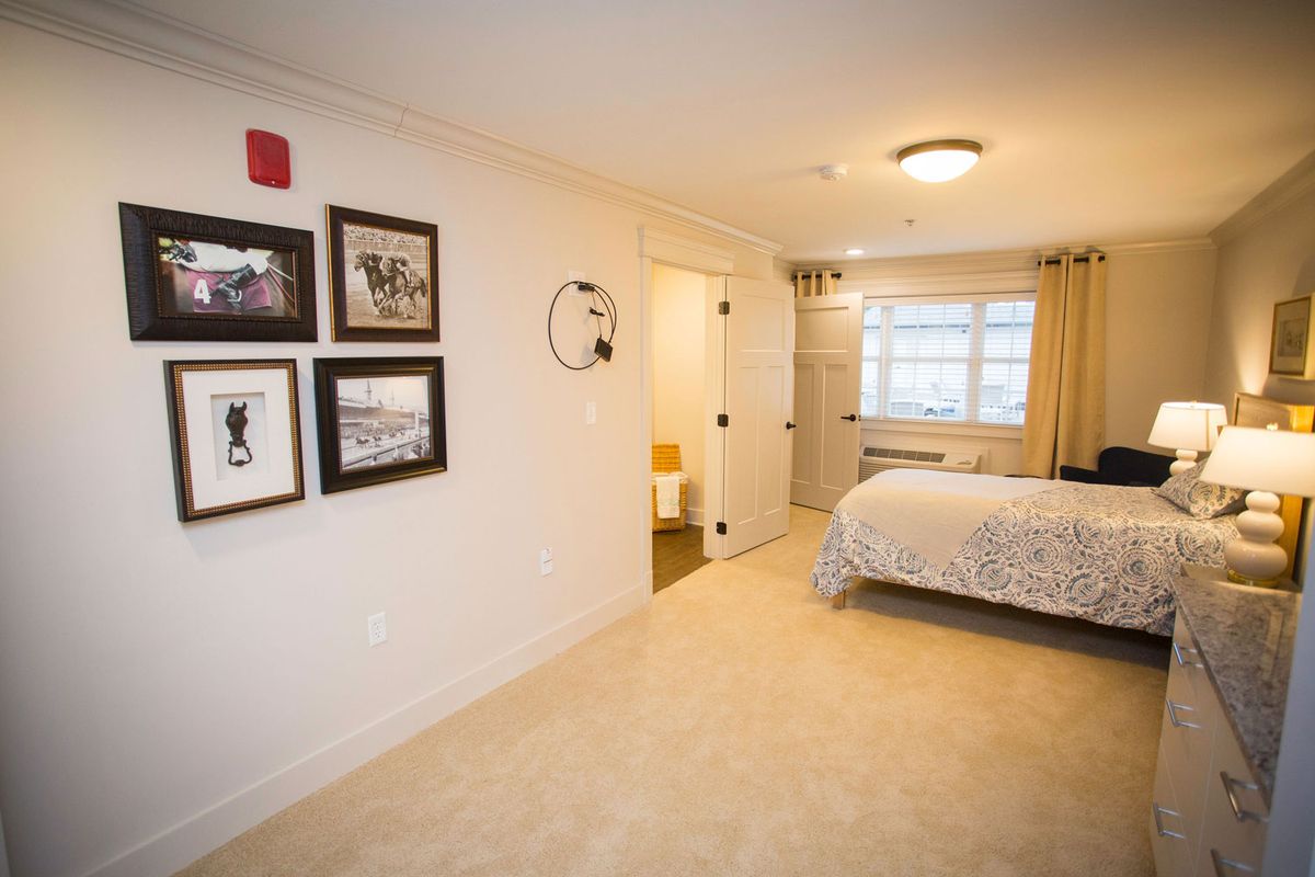 A cozy bedroom with wall art, a neatly made bed, and bright lighting.
