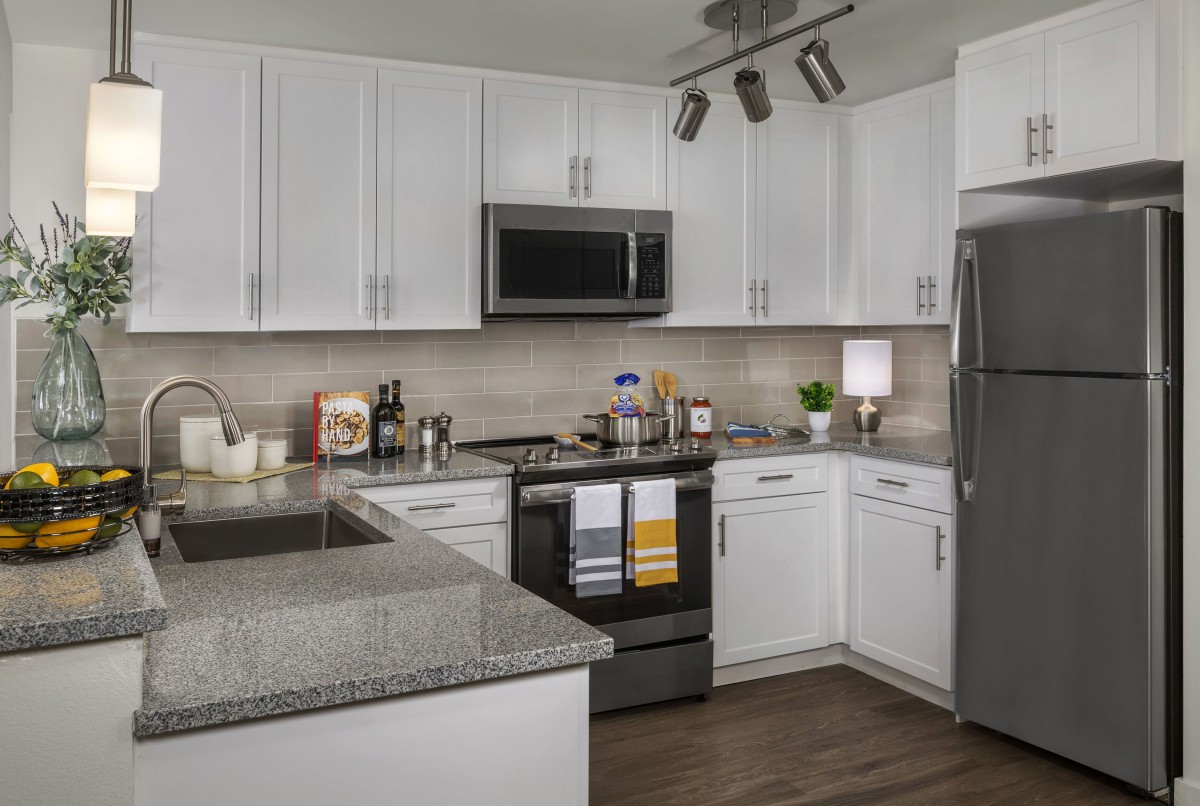 A modern kitchen featuring white cabinets and granite countertops.