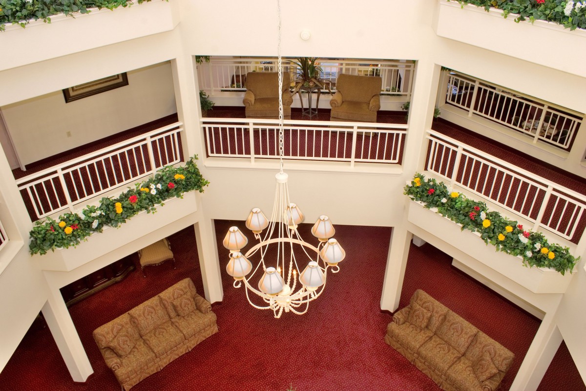 A spacious lobby with red carpet, cozy sofas, and a grand chandelier hanging from the ceiling.