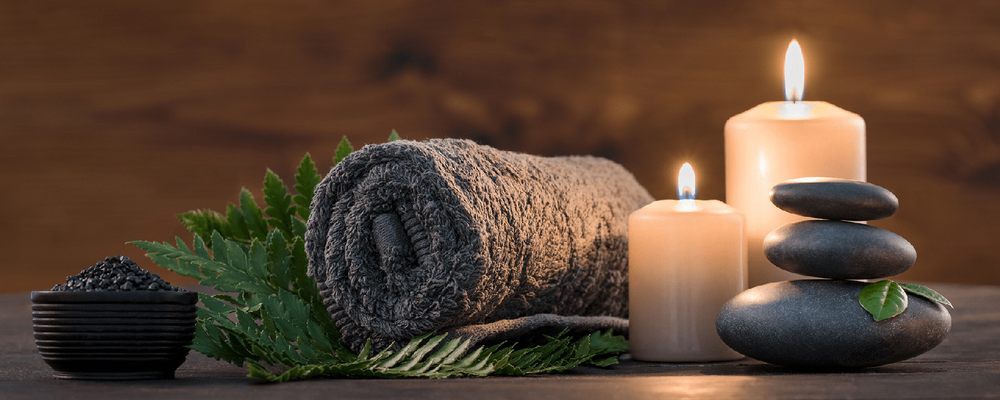 A rolled towel with a lit candle, creating a serene spa atmosphere.