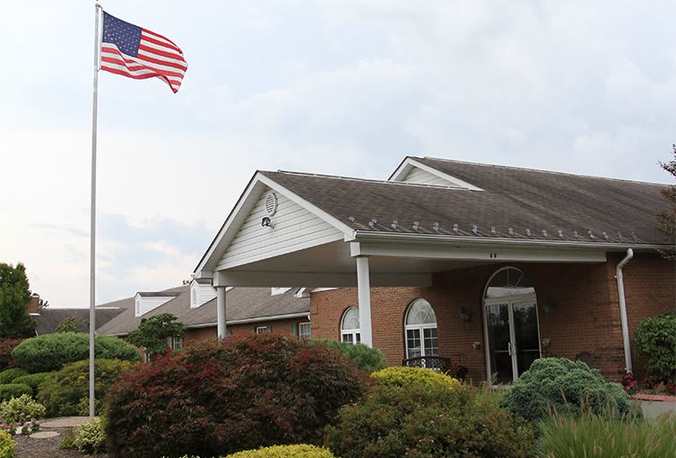 A brick building with an American flag and landscaped entrance.