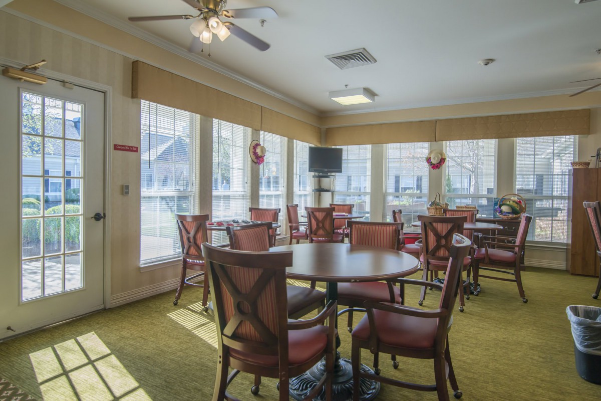 A well-lit dining room with tables and chairs, featuring large windows allowing natural light to fill the space.