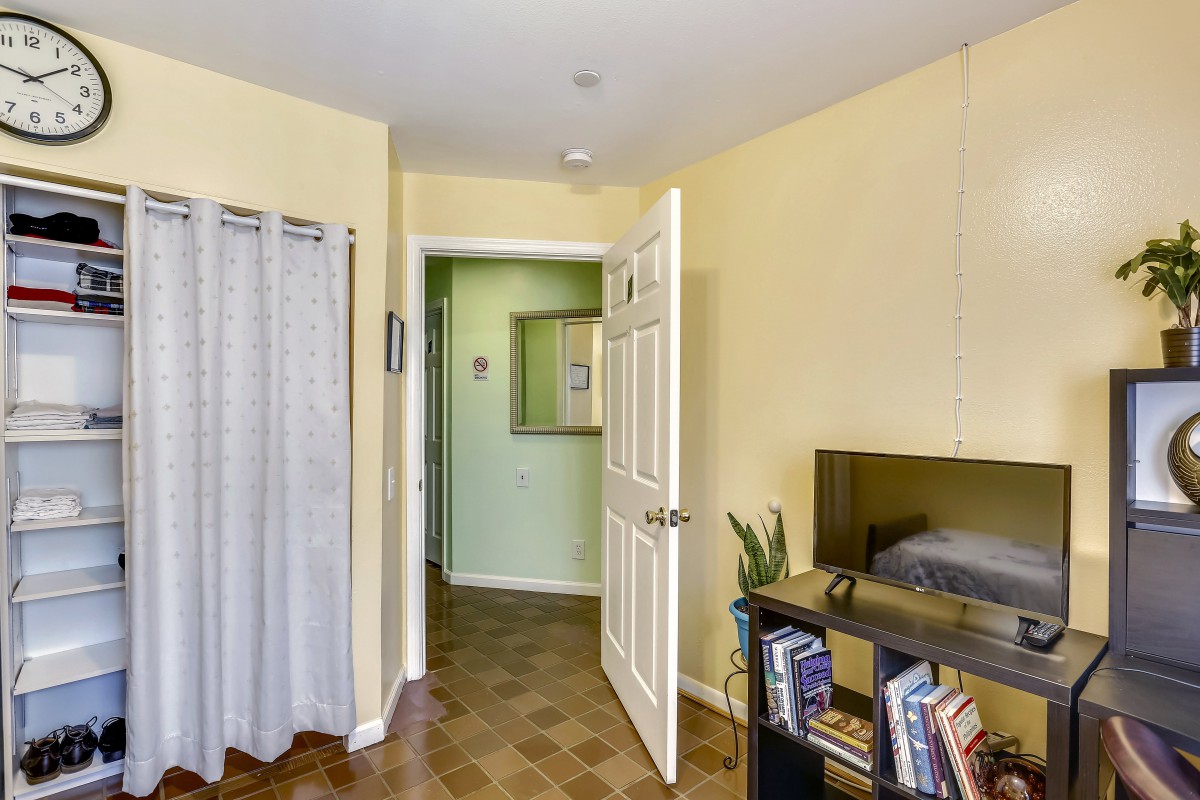 A cozy bedroom with a bookshelf and an open door leading to a hallway.