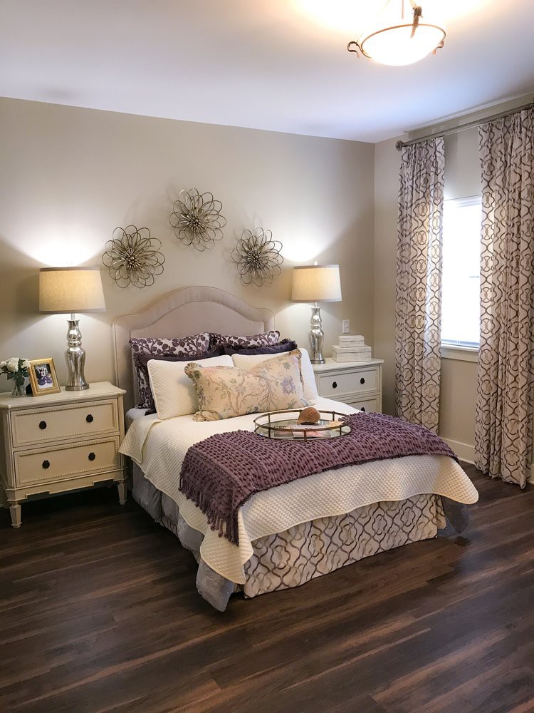 A cozy bedroom with elegant decor, featuring a well-made bed flanked by nightstands and lamps.