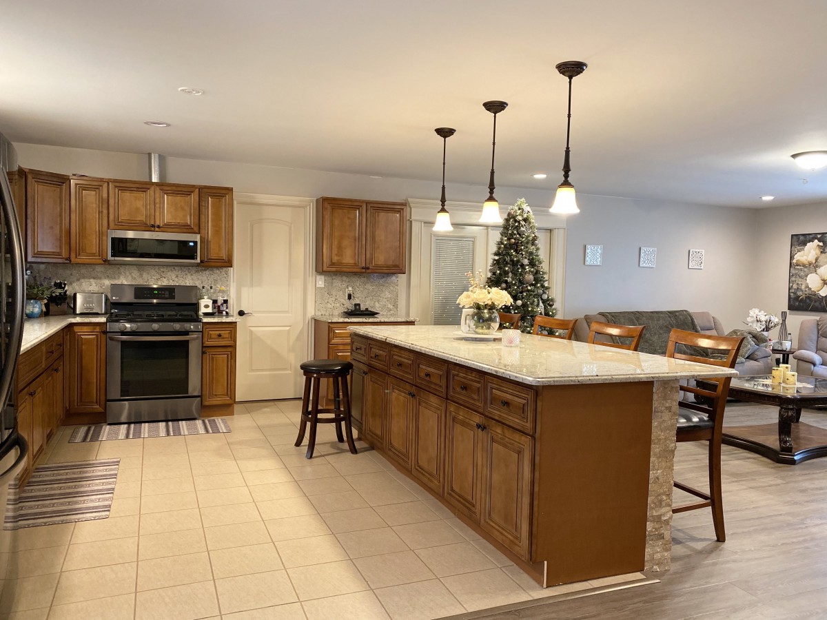 A modern kitchen with a large island, pendant lighting, and wood cabinets in an open concept space.
