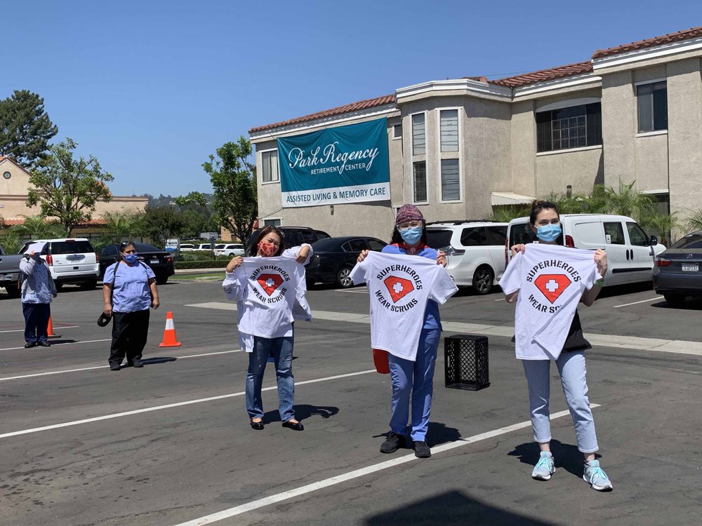 A group of people wearing masks, holding t-shirts, gathered in a parking lot.
