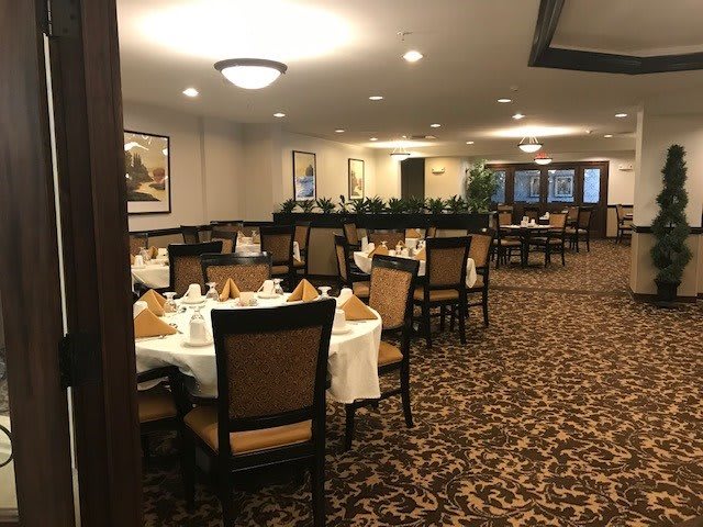 A formal dining area with neatly set tables and chairs.