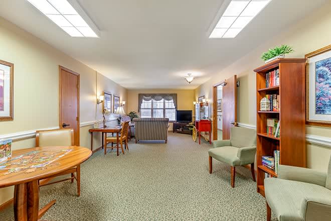 A cozy living room with seating, bookshelves, and a television.