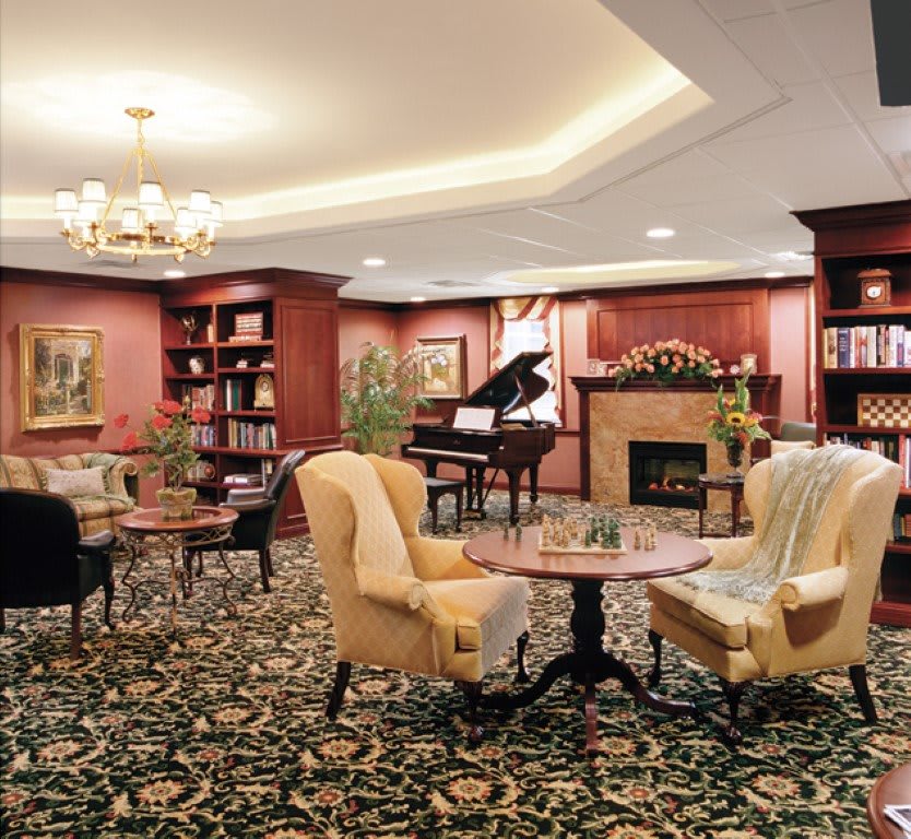 A cozy lounge area featuring a piano, fireplace, and comfortable seating.