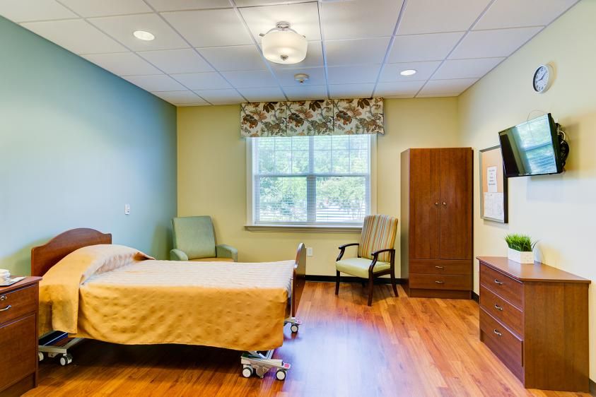 A well-furnished hospital room with a bed and seating area.