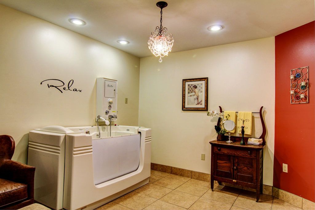 A luxurious and modern bathroom with a walk-in bathtub, elegant chandelier, and stylish decor.