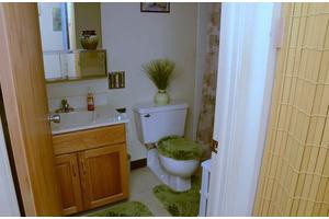 A bathroom with green rugs and decorative elements, featuring a toilet and sink.