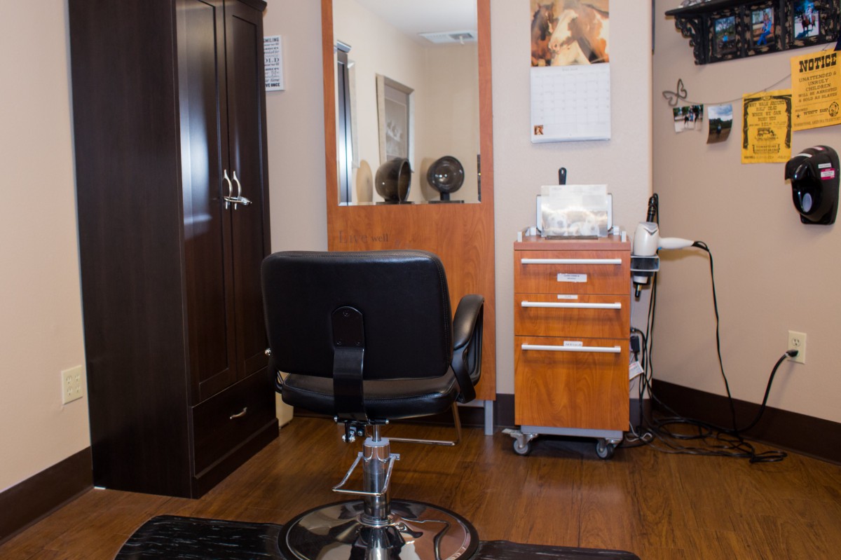 A well-organized hair salon with a styling chair, mirror, and storage cabinets.