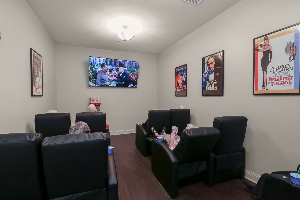 A cozy home theater room with recliner chairs and movie posters on the walls.
