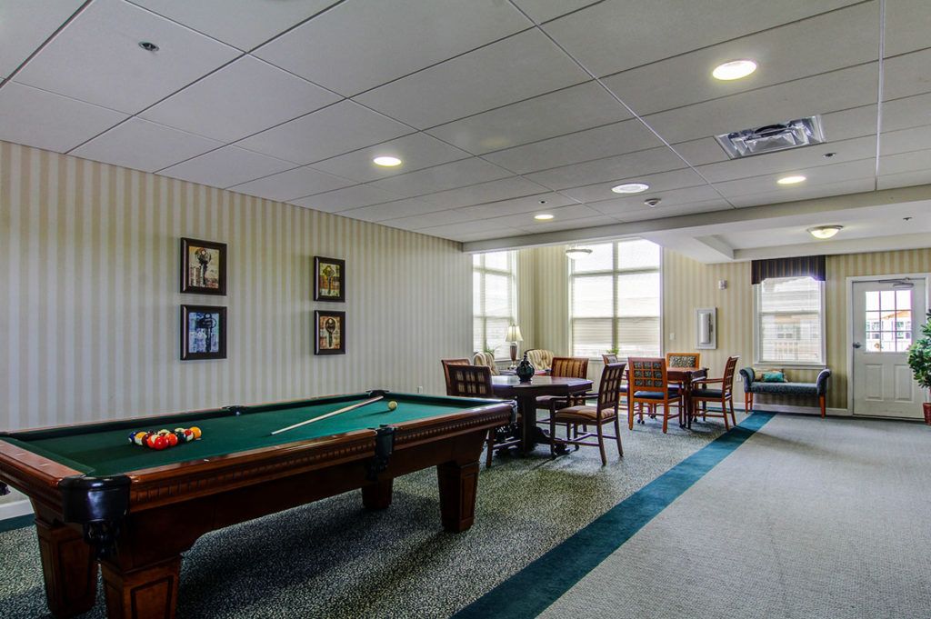 A recreation room featuring a pool table and seating area with tables and chairs.