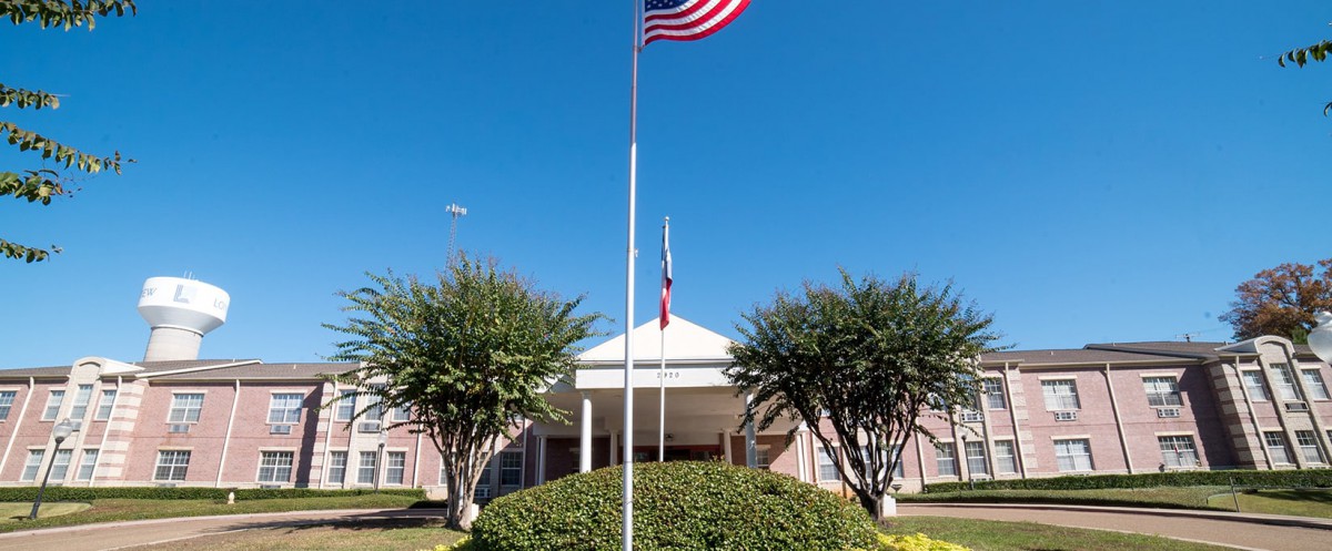 A building entrance with an American flag flying on a sunny day.