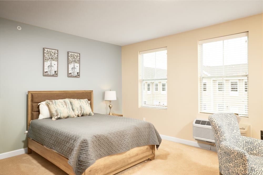 A modern bedroom with a comfortable bed, two large windows, and stylish decor.