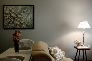 A cozy living room with a sofa, a floor lamp, and floral decorations.