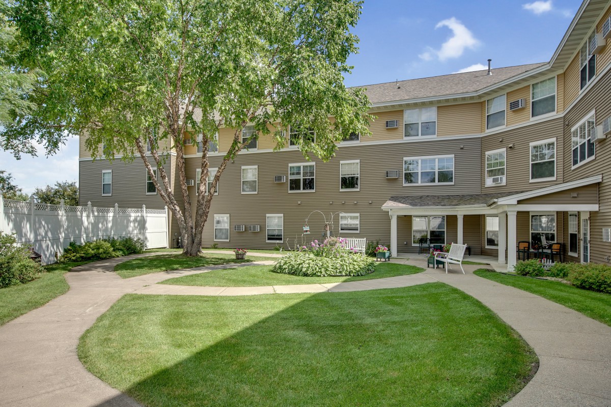 A well-maintained apartment building with a grassy courtyard and outdoor seating area.