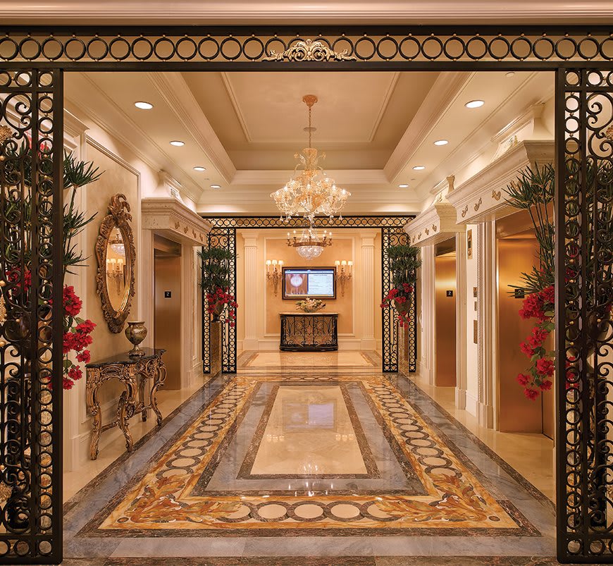 A luxurious lobby interior featuring ornate design elements, a central chandelier, and marble flooring.