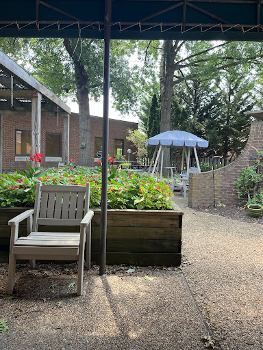 A serene garden patio featuring a comfortable chair, vibrant flowers, and a swing, perfect for relaxation.
