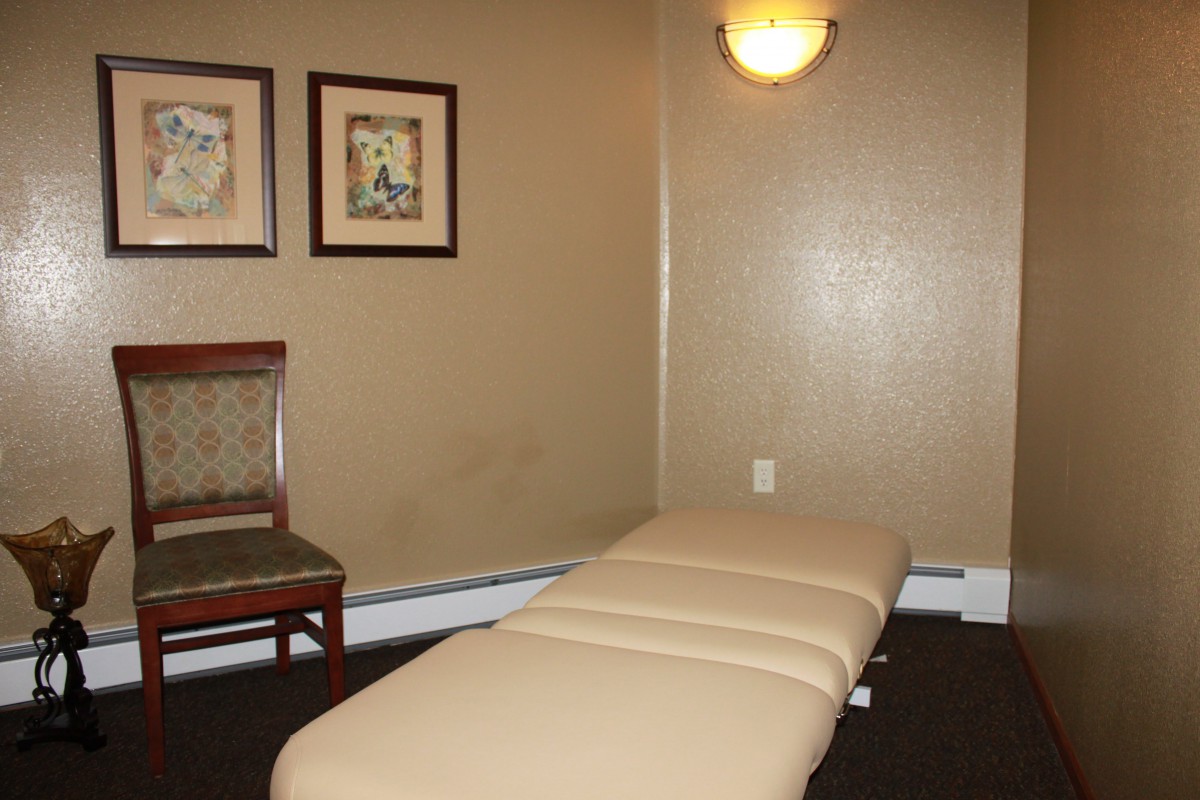 A cozy massage room with a treatment table and soft lighting.