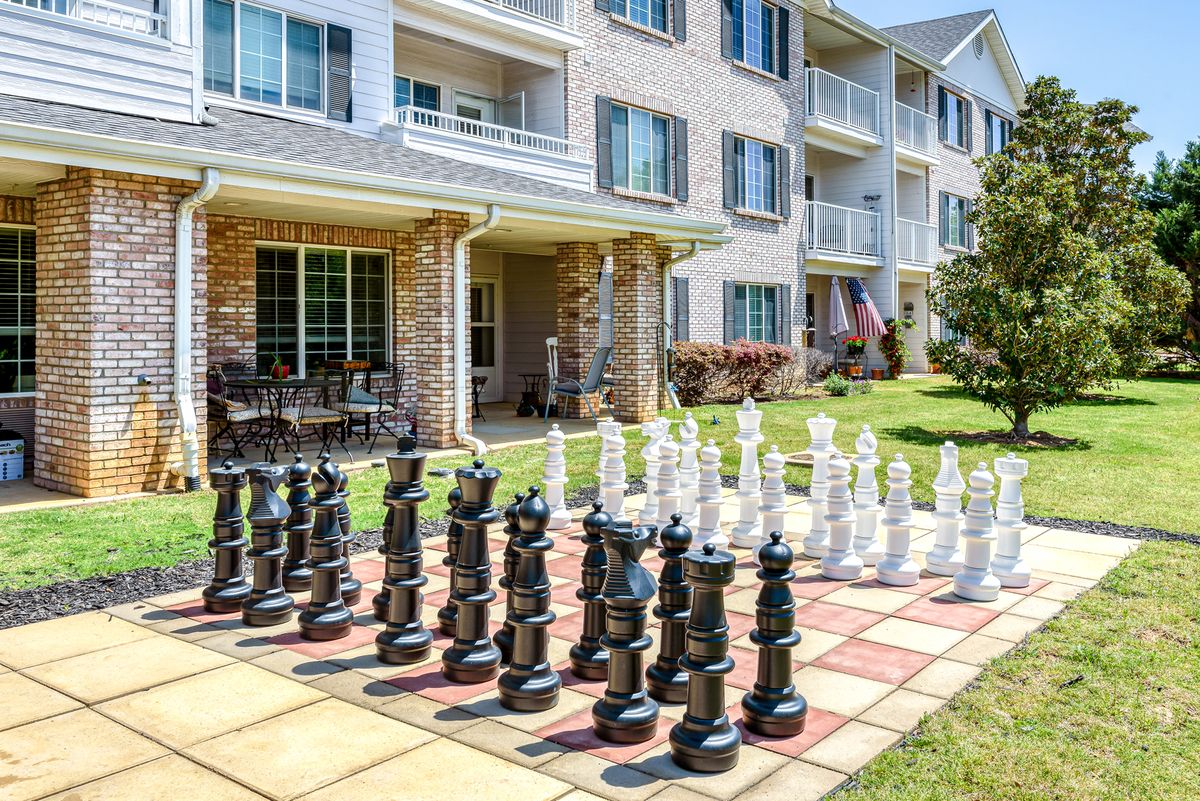 An outdoor giant chess set on a patio next to a residential building.