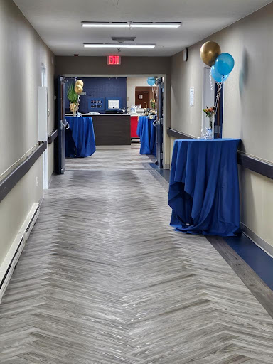 A decorated hallway set up for an event, featuring blue tables and festive balloons.