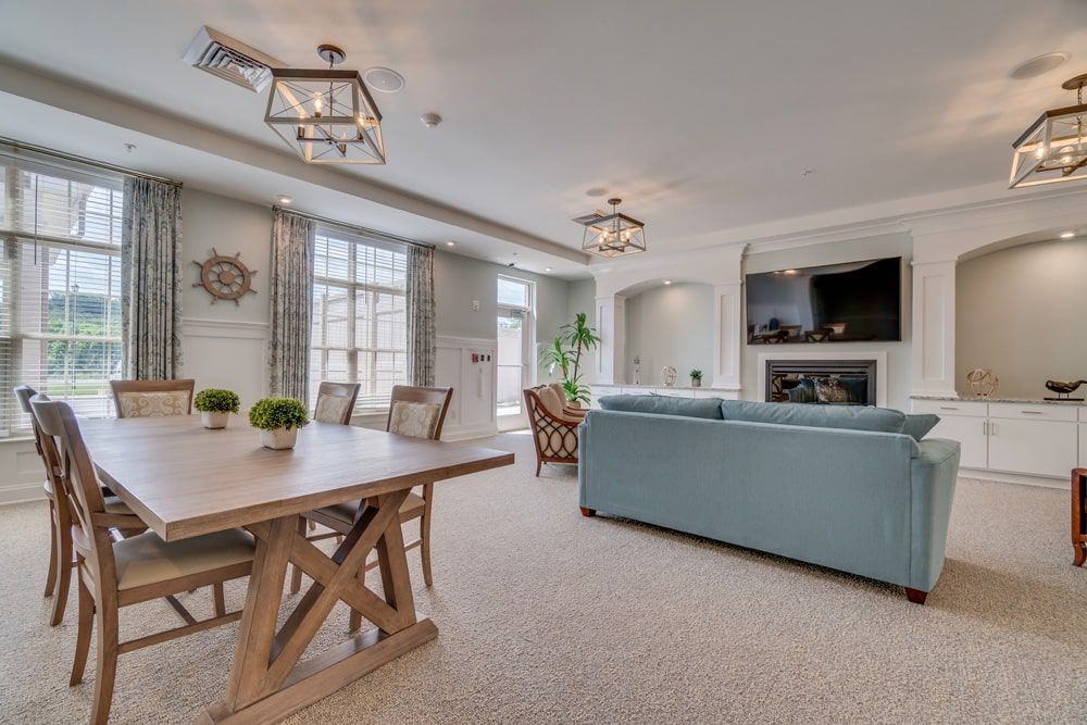Spacious and elegantly designed living room with a light blue sofa, wooden dining table, and modern lighting fixtures.