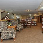 A comfortable library reading space with bookshelves and patterned chairs.