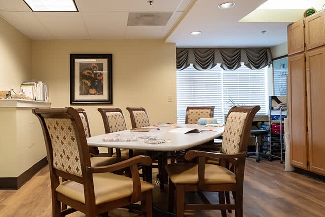 A well-appointed dining or meeting room with a large table and comfortable chairs, featuring decorative elements and natural light from the windows.