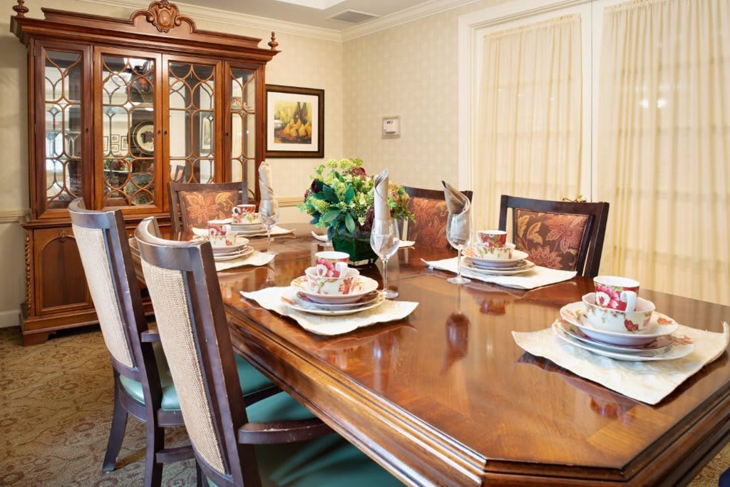 An elegant dining room with a formally set table, featuring a china cabinet and decorative elements.