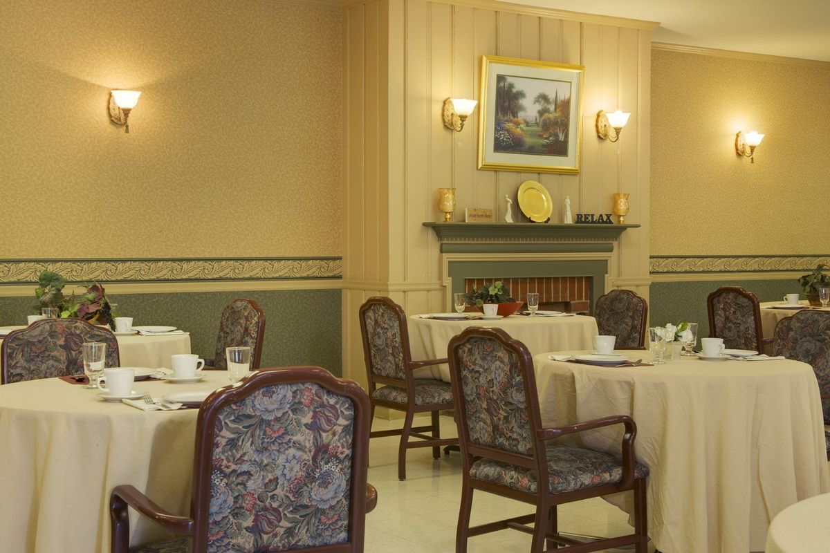 A cozy dining room with elegantly set tables, a fireplace, and decorative elements.