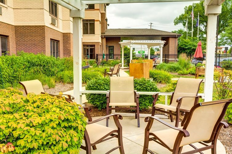 An inviting outdoor patio area with chairs surrounded by a lush garden landscaping.