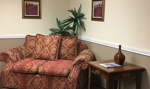 A cozy living room setting featuring a patterned couch, decorative plant, and wooden side table.