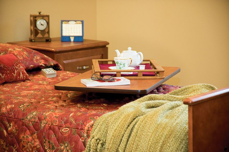 A cozy bedroom setting with a teapot on a tray and a soft blanket draped over the bed.