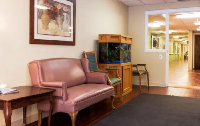 A comfortable waiting room featuring a pink sofa, an aquarium, and wall art.