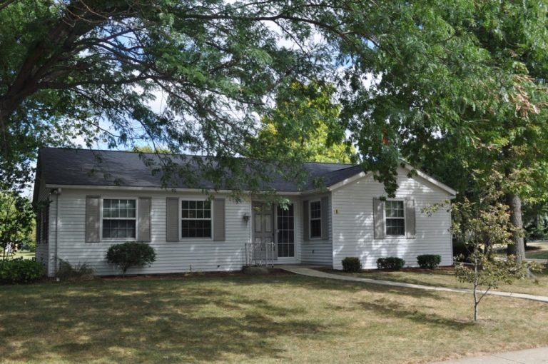 A cozy suburban house surrounded by trees and a well-maintained yard.