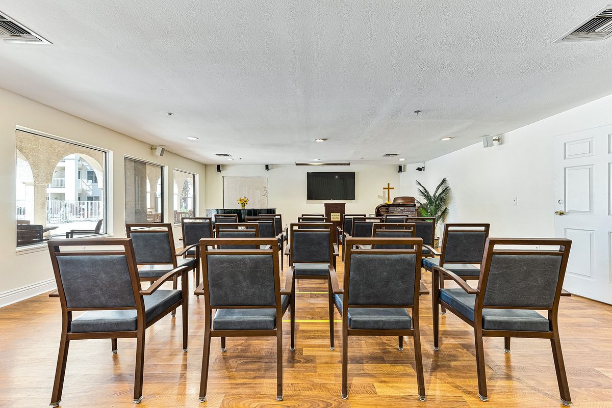 A modern conference room with neatly arranged chairs and a presentation screen at the front.